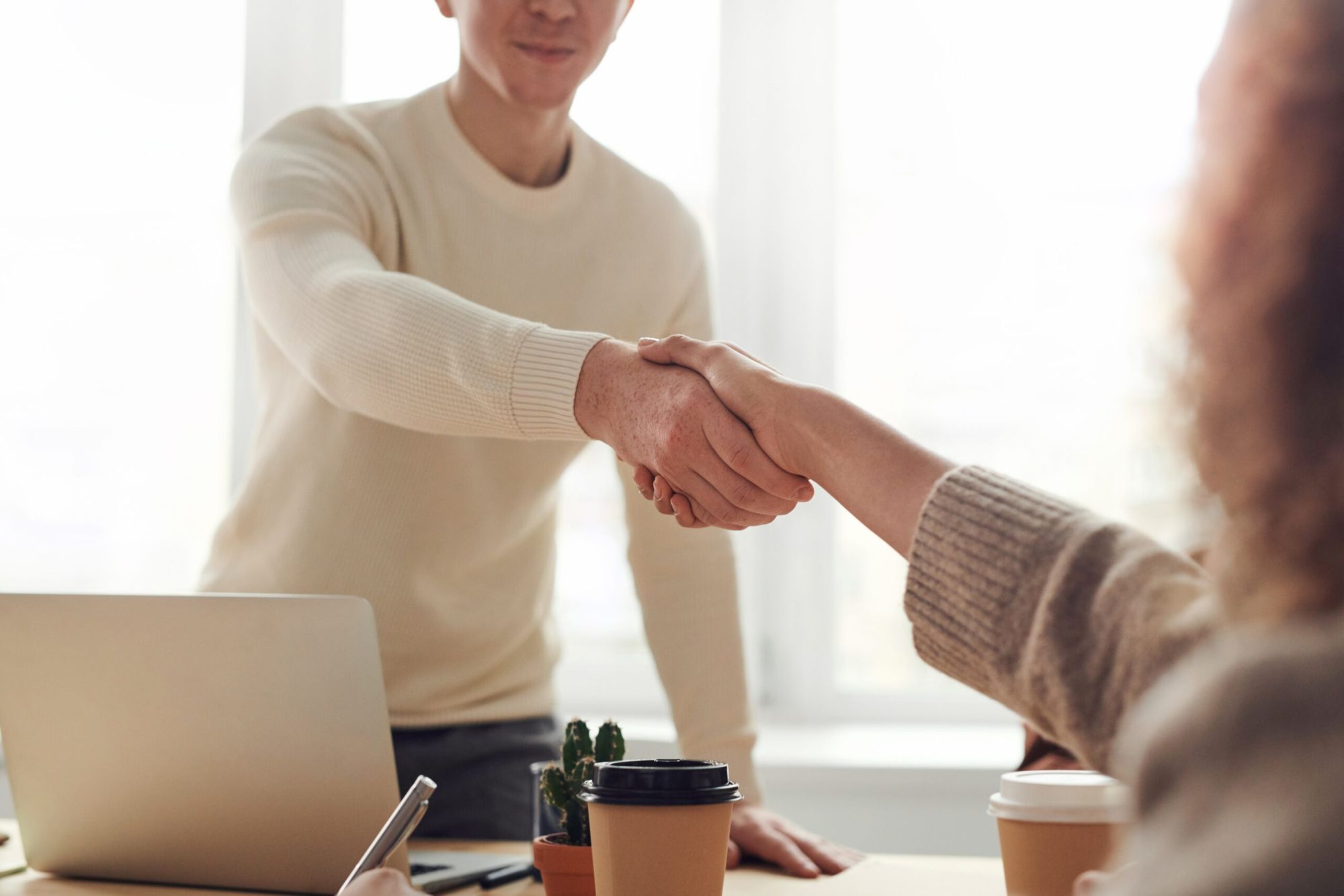 man shaking hands with women over coffee during a meeting 
